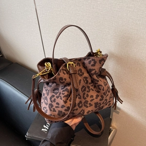 Retro leopard print bucket bag with brown leather handles and decorative side tassels