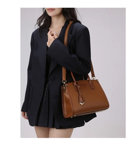 Brown textured leather tote with adjustable strap shown on a model in a navy suit