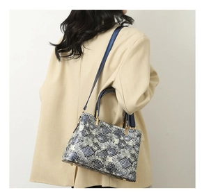 Close-up of blue snakeskin pattern tote bag with gold hardware worn on model shoulder