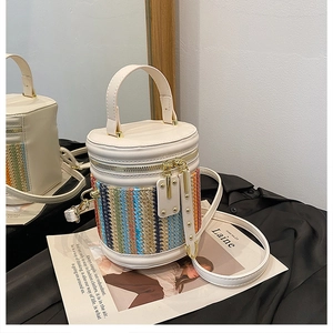 Detailed close-up of a cream cylindrical bucket bag with colorful woven texture on black fabric