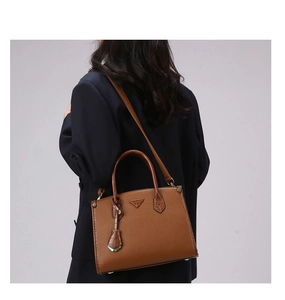 Detail of brown tote bag featuring lychee grain leather and crocodile texture trim