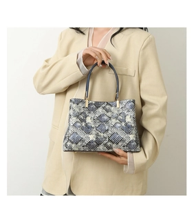 Detail of grey-blue snakeskin texture tote with blue handles and gold hardware