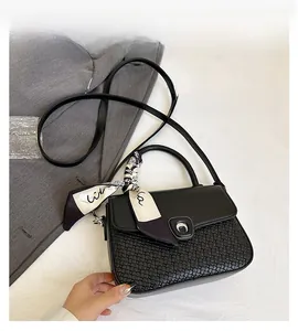 Detail of black woven shoulder bag with printed silk scarf handle and silver buckle