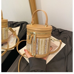 Close-up of woven bucket bag featuring khaki leather trim and golden metal zippers