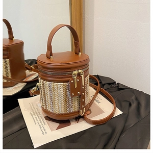 Detail of woven cylindrical bucket bag featuring brown PU leather and gold hardware accents