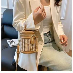 Detail of woven straw bucket bag with leather trim worn with a white blazer