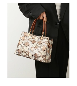 Close-up of stylish snakeskin pattern tote bag with golden hardware and brown handles