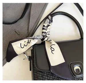Detail of a chic black and white twilly scarf wrapped around a quilted handbag handle