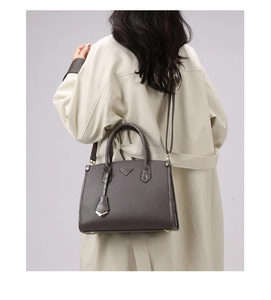 Detailed view of brown lychee leather tote bag with crocodile texture handle on shoulder