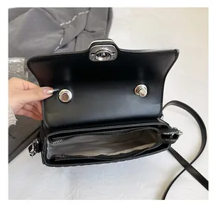 Detail of black leather shoulder bag showing double compartments and silver metal turn-lock