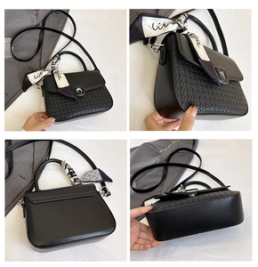 Detail of black crossbody bag featuring woven texture and silk scarf wrapped on handle