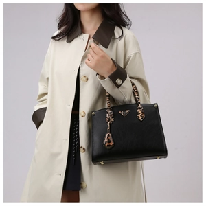 Detail of black pebbled leather tote with leopard print handle shown on a model