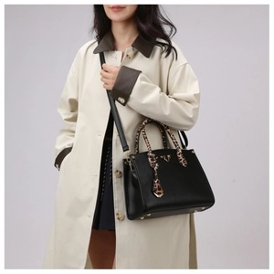 Detail of black pebbled leather tote with leopard print handles and gold hardware