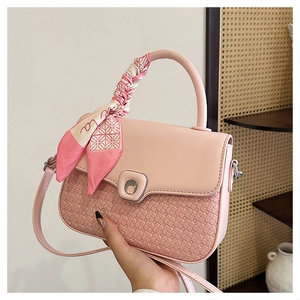 Detailed view of pink quilted handbag featuring silver metal clasp and decorative silk scarf