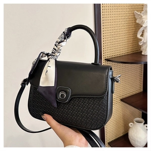 Detail of black woven crossbody bag with silk scarf handle and silver metal clasp