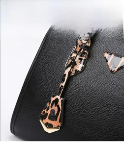 Detail view of black lychee grain leather and leopard print patchwork with gold hardware