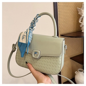 Close-up of mint green crossbody bag with woven texture and decorative silk scarf handle