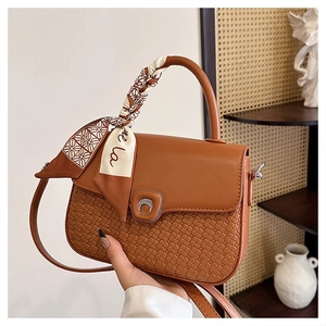 Detail of caramel brown patchwork bag with woven texture and decorative silk scarf