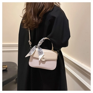 Detail of cream leather handbag featuring woven texture and decorative geometric scarf