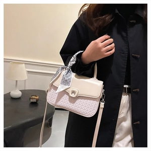 Detail of crossbody bag with woven texture, metal buckle and decorative scarf