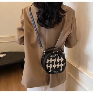 Detail of round black and white checkered crossbody bag with gold hardware finish