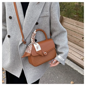 Detail of caramel leather shoulder bag with woven pattern and silk scarf handle
