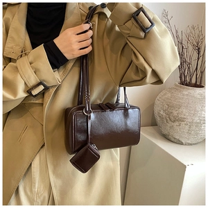 Detail of dark brown leather shoulder bag with a small detachable coin purse charm