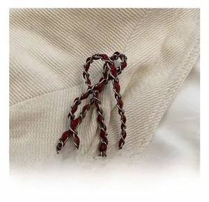 Detail der rot geflochtenen Leder-Silber-Metallkette auf beigem Cord-Hintergrund