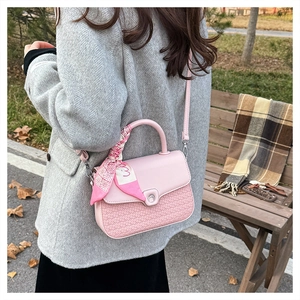 Detailed shot of pink woven crossbody bag with silk scarf handle and silver moon clasp