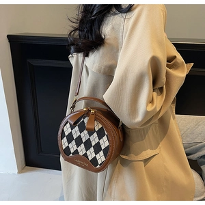 Detail of round crossbody bag featuring brown leather, bow accent and houndstooth pattern