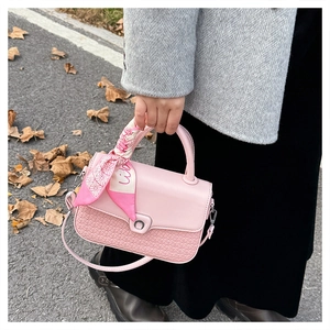 Detail of pink faux leather handbag with snake pattern texture and silk scarf handle