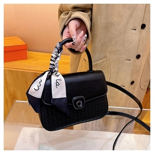 Close-up of black crossbody bag featuring a patterned silk scarf handle and metal clasp
