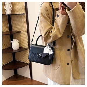 Detail of black woven shoulder bag with vintage metal clasp and polka dot scarf handle