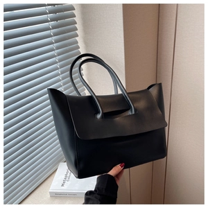 Detail of minimalist black matte leather tote bag with unique integrated handle design