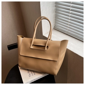 Detail of light brown tote bag showing the unique leather strap closure and matte finish