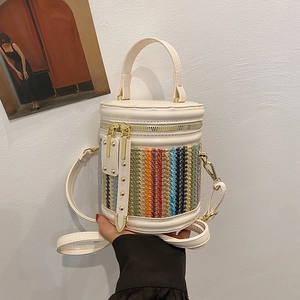 White woven bucket bag with colorful accents and top handle shown from a side view