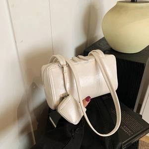 Minimalist beige underarm bag with matching coin pouch on a wooden stand