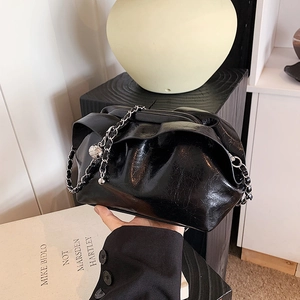 Elegante schwarze Cloud-Clutch mit silberner Gliederkette in Lifestyle-Umgebung