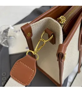 Close-up of golden metal hooks and leather stitching on a canvas tote bag