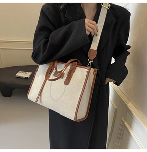 Detail of canvas tote bag with brown leather trim and adjustable wide fabric strap