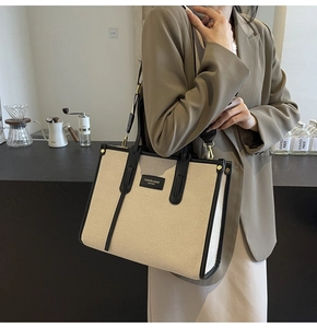 Detail of canvas tote with leather trim and fashion logo shown in a cafe setting