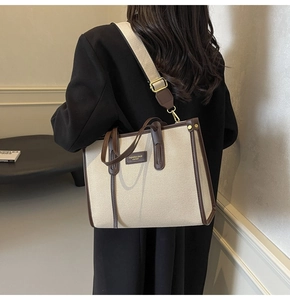 Detailed back view of a large canvas tote bag with brown leather trim and shoulder strap