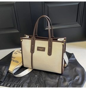 Detail of canvas tote bag with brown leather trim, handles and detachable strap