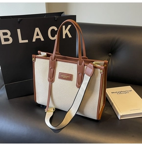 Detail of canvas tote bag showing brown leather trim and stylish adjustable wide strap