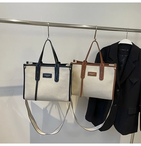 Detail of canvas tote bags with leather trim and adjustable shoulder straps on a hanger