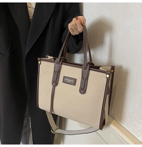 Close-up of beige canvas tote bag with brown leather trim and shoulder strap detail