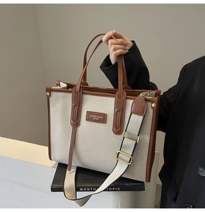 Detail of canvas tote bag with brown leather trim and detachable wide fabric shoulder strap
