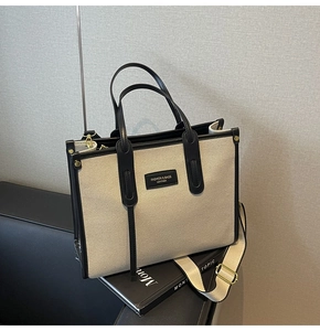 Detail of canvas tote bag with contrast leather trim, handles and adjustable shoulder strap