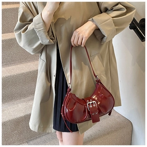 Detail of wine red patent leather shoulder bag with vintage pleats and silver buckle
