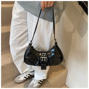 Detail of black pleated croissant bag featuring silver buckle and adjustable shoulder strap